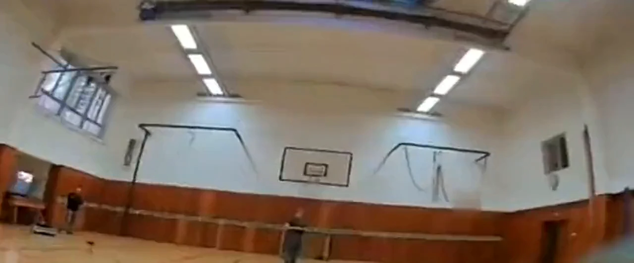 Pohled z FPV dronu při letu tělocvičnou